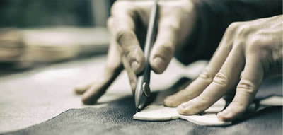 Bespoke shoes being made, photo shows leather being cut by hand